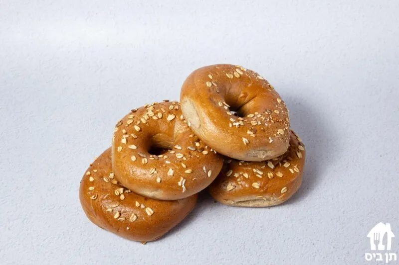בייגלים מצופים שומשום בערימה קטנה על רקע לבן
